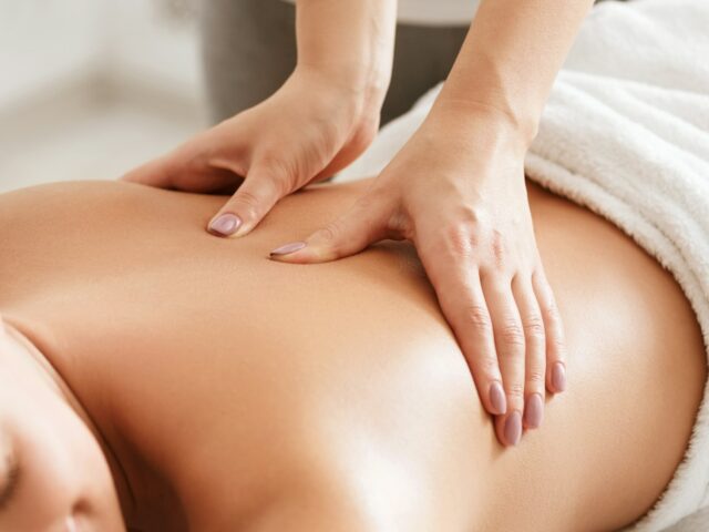 Body care. Young girl having massage, relaxing in spa salon