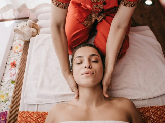 cropped view of masseur doing neck massage to woman in spa salon