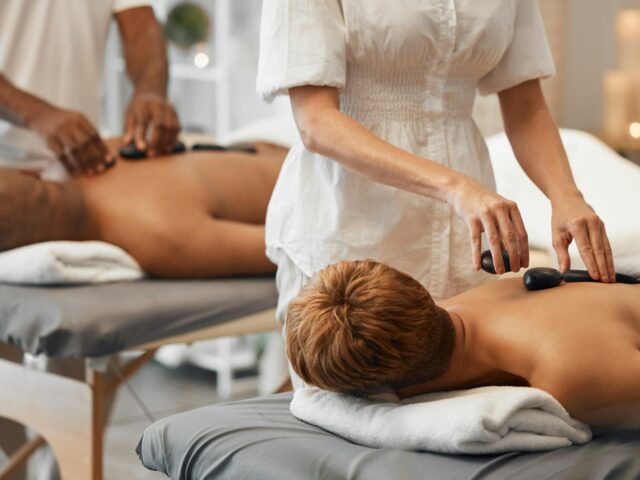 Hot stone massage, black couple and relax spa in skincare wellness, healthcare or stress management